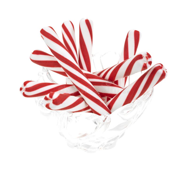 A group of peppermint candy sticks in a glass bowl on a white background. A group of peppermint candy sticks in a glass bowl on a white background.