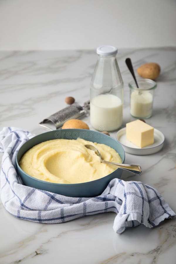 Шар с картофельными pap и продуктов, как картофель, молоко, соль, масло, мускатный орех полотенцем и точильщик на светлом фоне marble