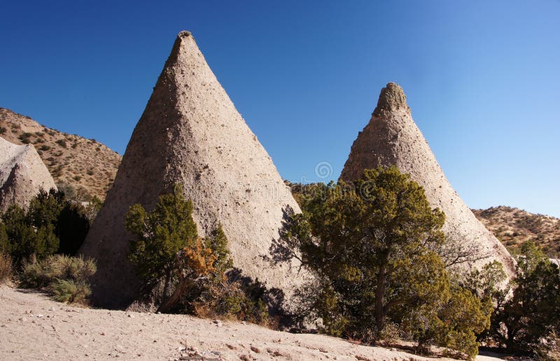 Kasha-Katuwe Tent Rocks National Monument, located 40 miles southwest of Santa Fe, New Mexico (near Cochiti), is a Bureau of Land Management (BLM) managed site that was established as a U.S. National Monument by President Bill Clinton in January 2001 shortly before leaving office. Kasha-Katuwe means white cliffs in the Pueblo language Keresan. The area owes its remarkable geology to layers of volcanic rock and ash deposited by pyroclastic flow from a volcanic explosion within the Jemez Volcanic Field that occurred 6 to 7 million years ago. Over time, weathering and erosion of these layers has created canyons and tent rocks. The tent rocks themselves are cones of soft pumice and tuff beneath harder caprocks, and vary in height from a few feet to 90 feet. The monument is open for day use only and may be closed by order of the Cochiti Pueblo Tribal Governor. A 1.2 mile (1.9 km) recreation trail leads up through a slot canyon to a lookout point where the tent rocks may be viewed from above. A 1.3 mile (2 km) loop trail leads past their base. The park is located on the Pajarito Plateau between 5700 and 6400 feet (1737–1951 m) above sea level. Kasha-Katuwe Tent Rocks National Monument, located 40 miles southwest of Santa Fe, New Mexico (near Cochiti), is a Bureau of Land Management (BLM) managed site that was established as a U.S. National Monument by President Bill Clinton in January 2001 shortly before leaving office. Kasha-Katuwe means white cliffs in the Pueblo language Keresan. The area owes its remarkable geology to layers of volcanic rock and ash deposited by pyroclastic flow from a volcanic explosion within the Jemez Volcanic Field that occurred 6 to 7 million years ago. Over time, weathering and erosion of these layers has created canyons and tent rocks. The tent rocks themselves are cones of soft pumice and tuff beneath harder caprocks, and vary in height from a few feet to 90 feet. The monument is open for day use only and may be closed by order of the Cochiti Pueblo Tribal Governor. A 1.2 mile (1.9 km) recreation trail leads up through a slot canyon to a lookout point where the tent rocks may be viewed from above. A 1.3 mile (2 km) loop trail leads past their base. The park is located on the Pajarito Plateau between 5700 and 6400 feet (1737–1951 m) above sea level.