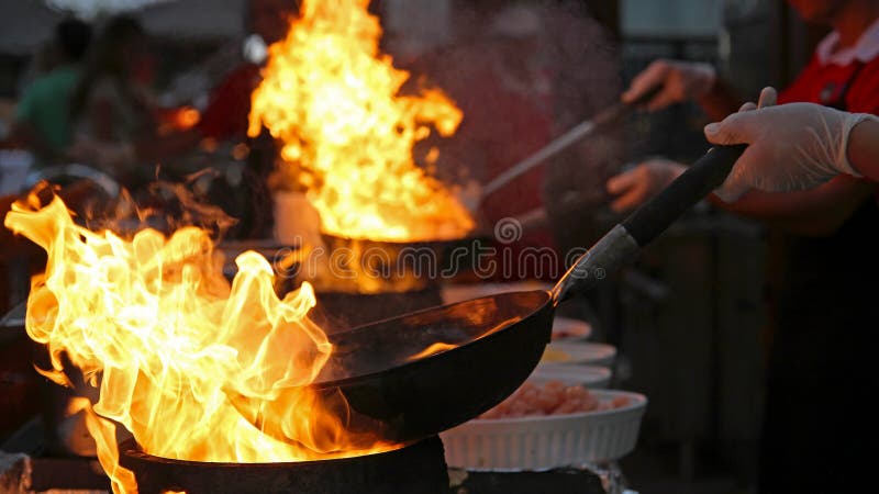 Шеф-повар Flambe варя в внешней кухне стоковое изображение rf Шеф-повар Flambe варя в внешней кухне стоковое изображение rf