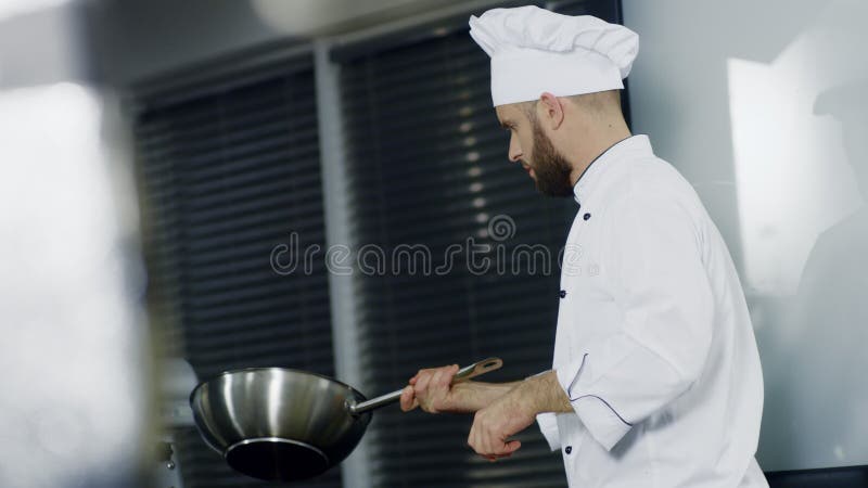 Шеф-повар варя во вке на ресторане кухни Шеф-повар человека подготавливая азиатскую еду в лотке