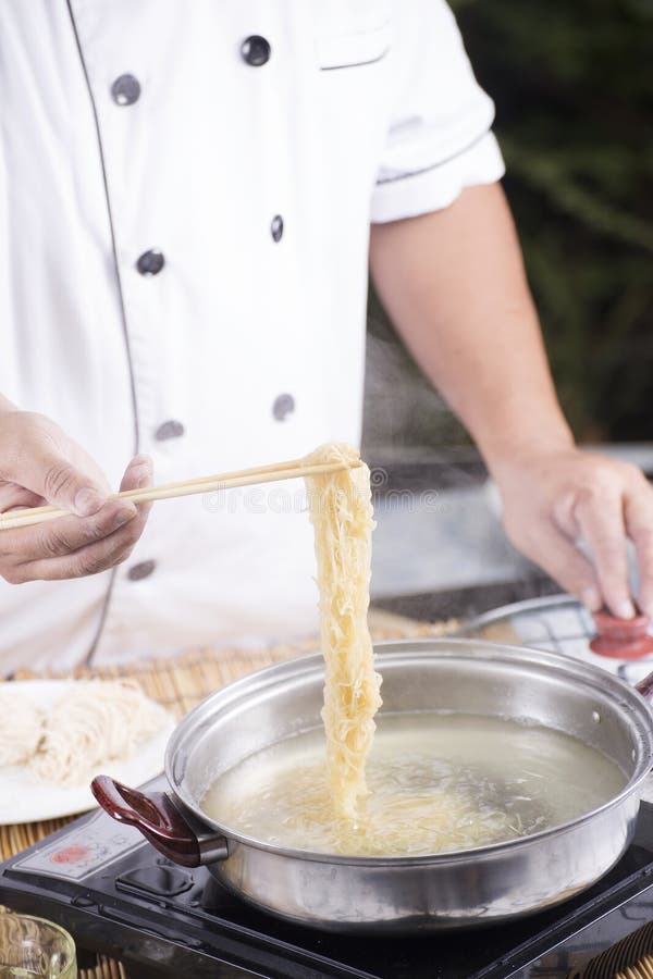 Chef holding the noodle from the pot with chopsticks / Cooking Noodle concept. Chef holding the noodle from the pot with chopsticks / Cooking Noodle concept