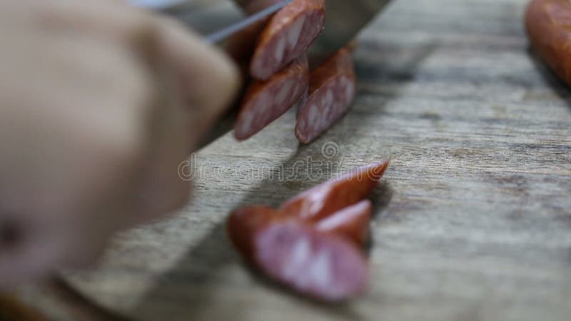 Шеф-повар режет Wienerwurst на деревянной круглой доске