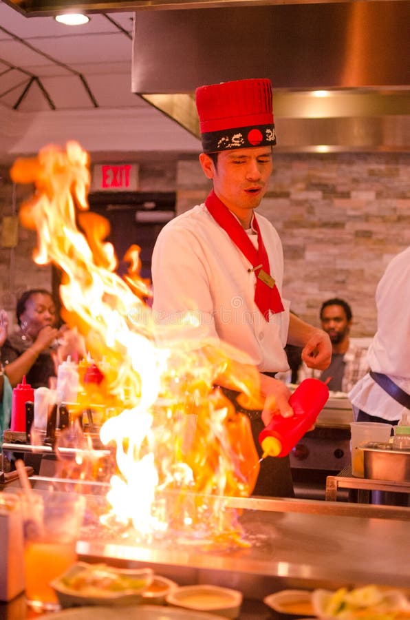 Asian japanese hibachi cook makes meal while guests have fun watching his antics and moves. Asian japanese hibachi cook makes meal while guests have fun watching his antics and moves