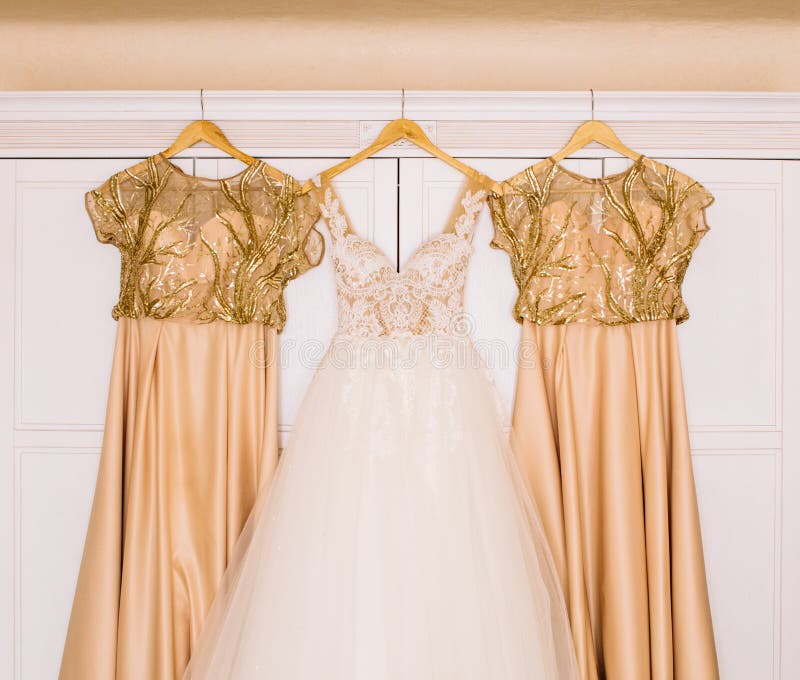 Шикарное платье свадьбы и бежевые мантии для bridesmaids висят сверх стоковые фото Шикарное платье свадьбы и бежевые мантии для bridesmaids висят сверх стоковые фото