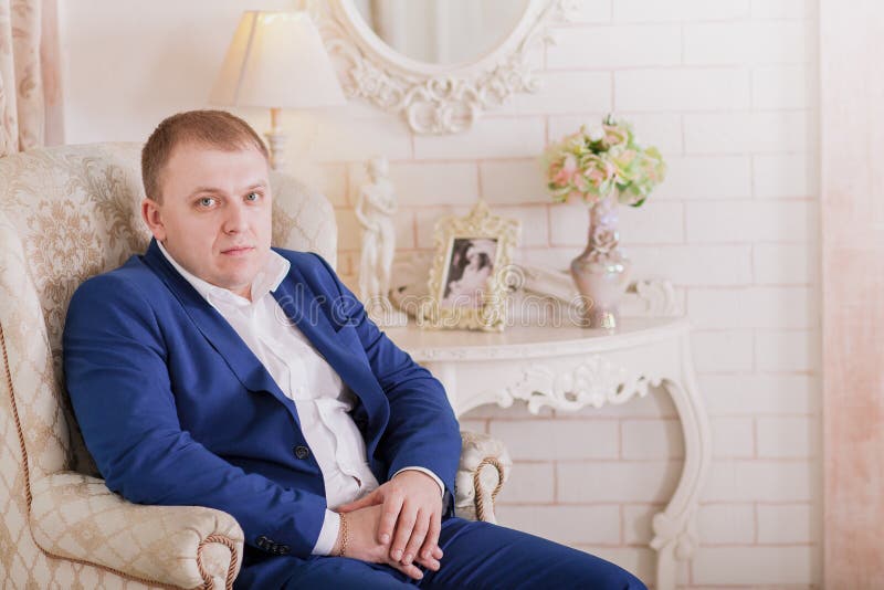 Шикарный усмехаясь groom Красивый человек в сюите при петлица сидя на силле окна внутри помещения стоковые изображения rf