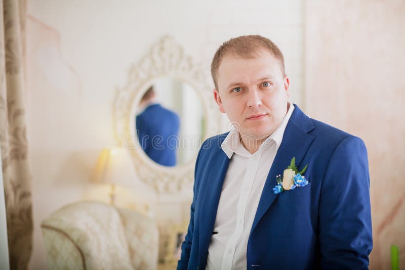 Шикарный усмехаясь groom Красивый человек в сюите при петлица сидя на силле окна внутри помещения стоковое изображение