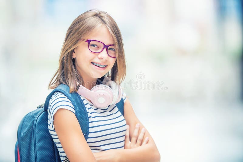 Schoolgirl with bag, backpack. Portrait of modern happy teen school girl with bag backpack headphones and tablet. Girl with dental braces and glasses. Schoolgirl with bag, backpack. Portrait of modern happy teen school girl with bag backpack headphones and tablet. Girl with dental braces and glasses.