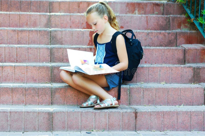 Школьница 8 лет старой делая домашней работы на лестницах читает книгу стоковые изображения Школьница 8 лет старой делая домашней работы на лестницах читает книгу стоковые изображения