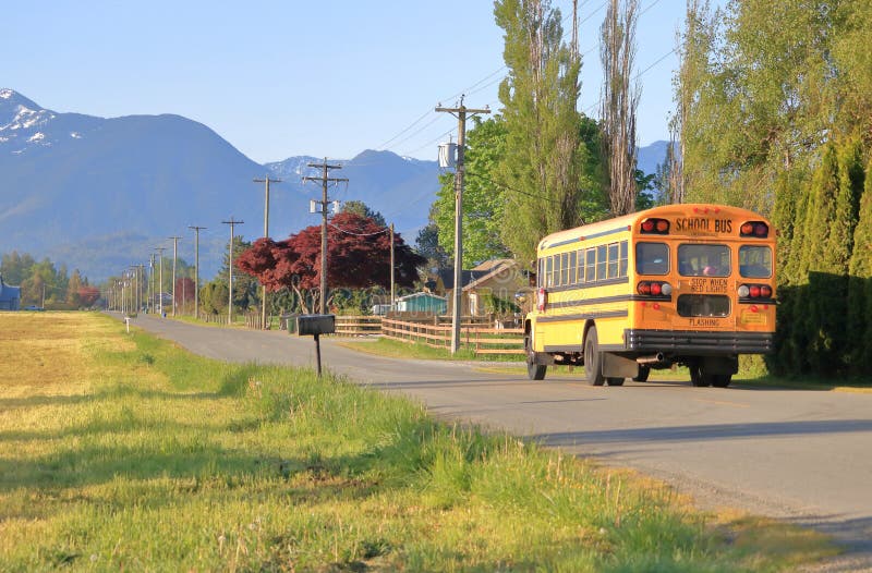 A morning rural school bus drives through a quiet country road in a beautiful agricultural valley. A morning rural school bus drives through a quiet country road in a beautiful agricultural valley.