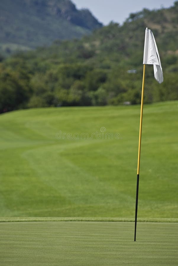 Flagpole is positioned to the right of the frame, behind that the fairway approach of one of the holes, showing also the thick rough bush area that surrounds all the holes of the Sun City Gary Player Golf Course. Flagpole is positioned to the right of the frame, behind that the fairway approach of one of the holes, showing also the thick rough bush area that surrounds all the holes of the Sun City Gary Player Golf Course.