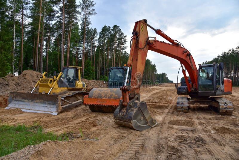 Экскаватор бульдозера и compactor почвы на дорожной работе. Тяжелые earthmoving строительная техника и оборудование в ходе земли стоковая фотография rf