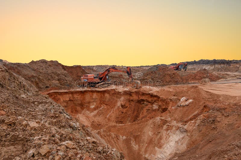 Экскаватор во время earthmoving на открытом карьере на фоне заката. Строительная техника и earthmoving тяжелое оборудование. Тяжел стоковые фотографии rf