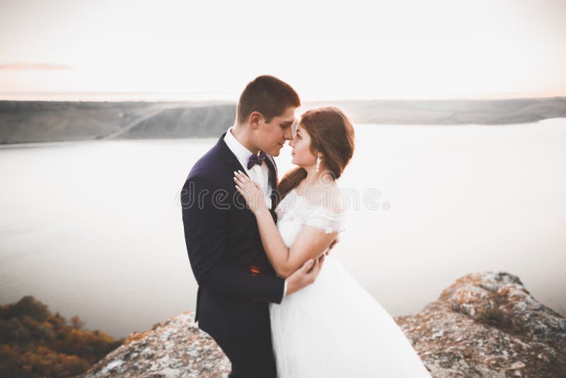 Элегантные стильные счастливые пары свадьбы, невеста, шикарный groom на предпосылке моря и небо стоковые изображения Элегантные стильные счастливые пары свадьбы, невеста, шикарный groom на предпосылке моря и небо стоковые изображения