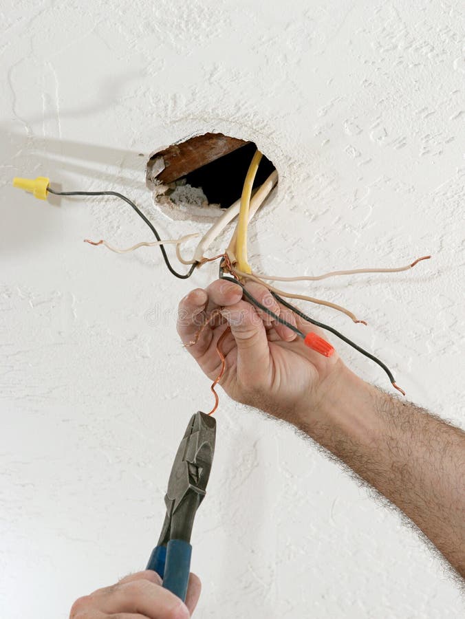 A closeup of an electrician's hands as he uses pliers to straighten electrical wires. Work is being performed to code by a licensed master electrician. A closeup of an electrician's hands as he uses pliers to straighten electrical wires. Work is being performed to code by a licensed master electrician.