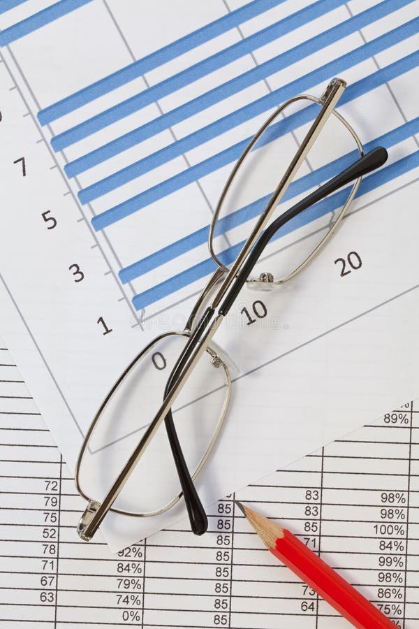 A pencil and glasses lying on a spreadsheet and chart. A pencil and glasses lying on a spreadsheet and chart