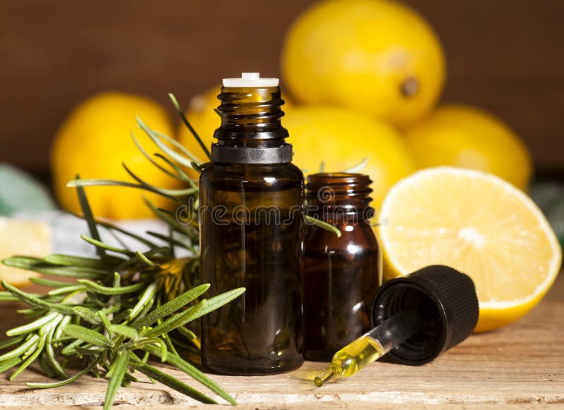 Lemon essential oil, lemon fruit and rosemary on wooden background. Lemon essential oil, lemon fruit and rosemary on wooden background