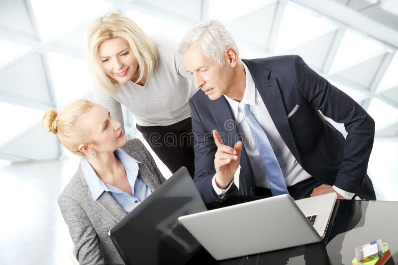 Portrait of business people sitting at desk in front of laptop and consulting from business plan. Teamwork at office. Portrait of business people sitting at desk in front of laptop and consulting from business plan. Teamwork at office.