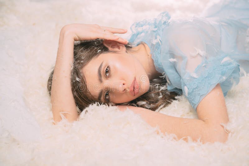 Я хочу остаться в кровати Милая девушка в женском белье nightie с пером в длинных волосах Милая девушка ослабляя на кровати пера стоковое изображение rf