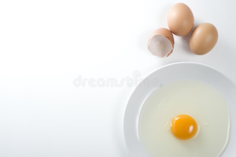 Opened egg in a plate and whole eggs by the side. Opened egg in a plate and whole eggs by the side