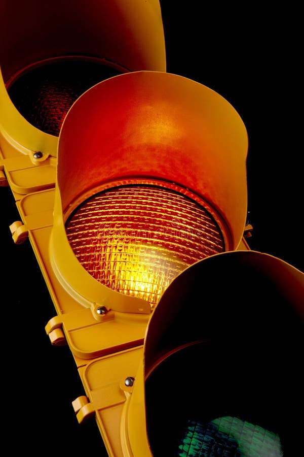 Close up of traffic light with illuminated amber lens. Close up of traffic light with illuminated amber lens