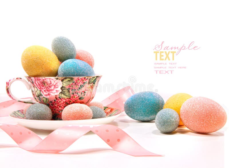 Brightly colored eggs in tea cup on white. Brightly colored eggs in tea cup on white