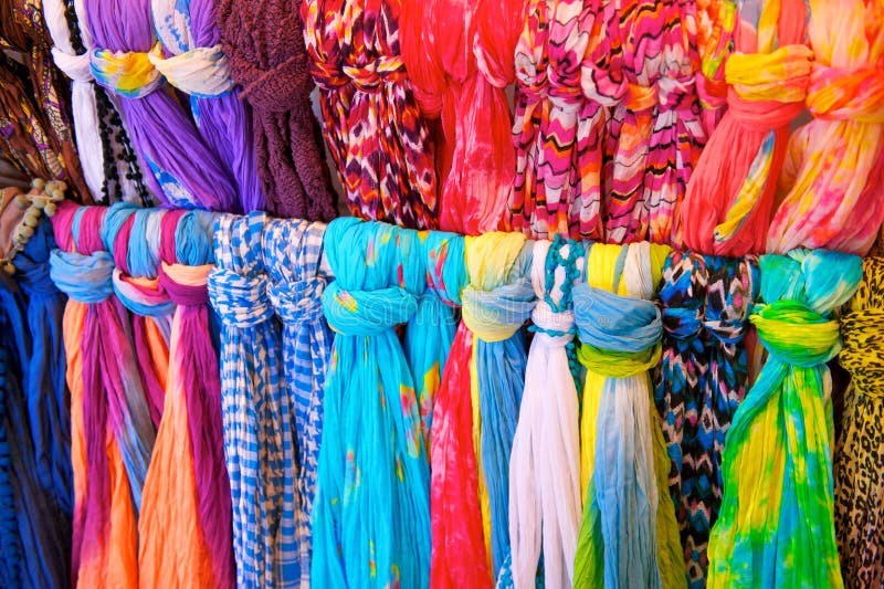 Two rows of brightly colored scarves tied to a rack in a clothing store. Two rows of brightly colored scarves tied to a rack in a clothing store