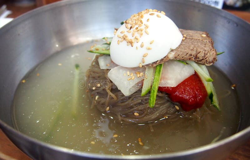 Clear noodle soup with Korean style sauce and boiled egg on stainless steel bowl. Clear noodle soup with Korean style sauce and boiled egg on stainless steel bowl