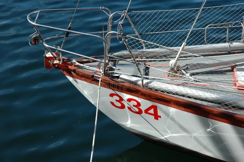 The front of a yacht at sea on a calm day. Detail of the boat is white, with some red inset details. The front of a yacht at sea on a calm day. Detail of the boat is white, with some red inset details.