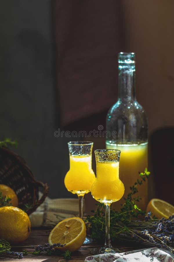 ? Limoncello in Grappas wineglass mit Wassertropfen und Lavendel Künstlerisches Stillleben im dunklen Hintergrund mit sonniger Be lizenzfreie stockfotos ? Limoncello in Grappas wineglass mit Wassertropfen und Lavendel Künstlerisches Stillleben im dunklen Hintergrund mit sonniger Be lizenzfreie stockfotos