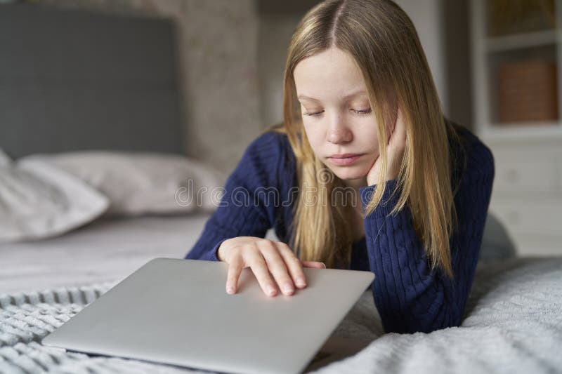 Unhappy Teenage Girl Closing Laptop Lying On Bed At Home Anxious About Social Media Online Bullying And Being Online Too Much. Unhappy Teenage Girl Closing Laptop Lying On Bed At Home Anxious About Social Media Online Bullying And Being Online Too Much