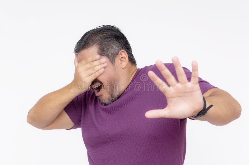 A middle aged guy covering his eyes while refusing look, begging someone to stop. Blinded by a light or afraid by a disturbing sight. Isolated on a white background. A middle aged guy covering his eyes while refusing look, begging someone to stop. Blinded by a light or afraid by a disturbing sight. Isolated on a white background.