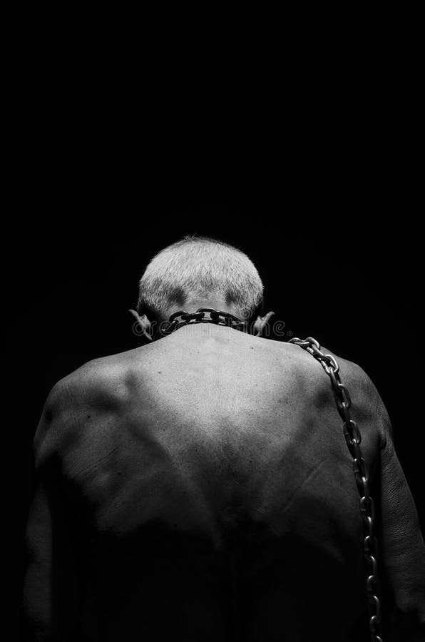 Slavery. A man tied with a chain over his neck in black and white. Slavery. A man tied with a chain over his neck in black and white