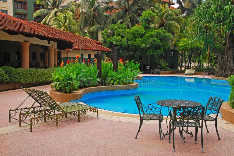 Rounded Blue Pool with Greens of a Condominium Property with deckchair and table chair in Kuala Lumpur. Rounded Blue Pool with Greens of a Condominium Property with deckchair and table chair in Kuala Lumpur