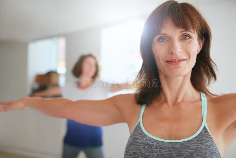 Portrait of fit mature women in a meditative yoga pose at gym. Healthy female model doing padmasana at health club. Portrait of fit mature women in a meditative yoga pose at gym. Healthy female model doing padmasana at health club.