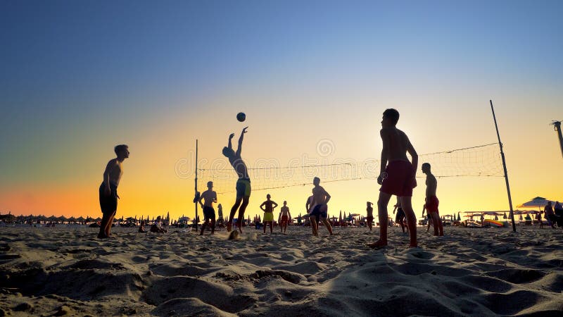 一个小组的剪影打沙滩排球的青年人