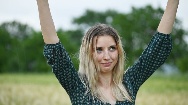 一个愉快的可爱的白种人白肤金发的女孩的特写镜头画象有湿头发的在自然的雨期间室外在a