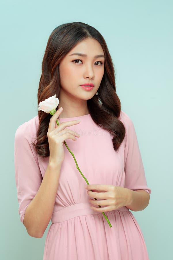 一个拿着粉红玫瑰的快乐美丽的年轻女子 免版税库存照片