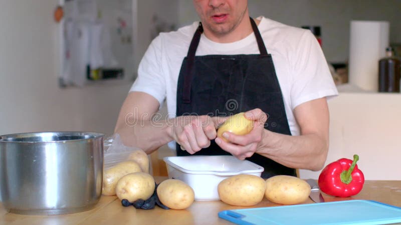 一个男人在厨房里用土豆和新鲜蔬菜熟练地做饭 影视素材