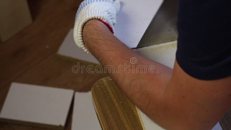 一个男人用钢锯沿着标线切板. 用铅笔标记工件编号. 在家做家具