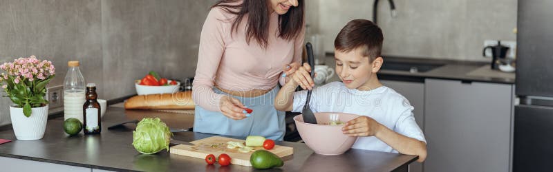 一个白人快乐的母亲在家教小儿子做蔬菜沙拉.