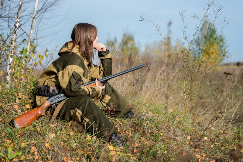 Portrait of a beautiful girl in white camouflage hunter with a gun on a background of deciduous forest. Portrait of a beautiful girl in white camouflage hunter with a gun on a background of deciduous forest