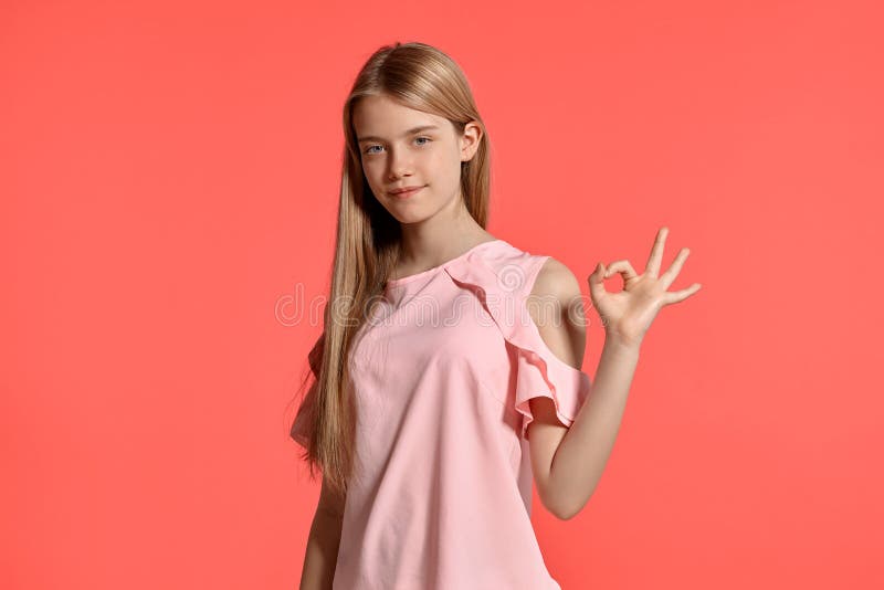 一个美女白肤金发的少年的演播室画象摆在桃红色背景的一件玫瑰色T恤杉的 免版税图库摄影 一个美女白肤金发的少年的演播室画象摆在桃红色背景的一件玫瑰色T恤杉的 免版税图库摄影