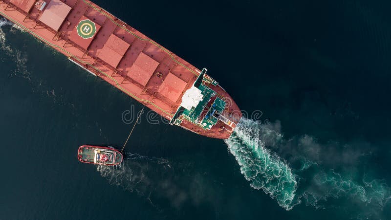 航拍一艘货轮在拖船的帮助下驶近港口 免版税库存图片