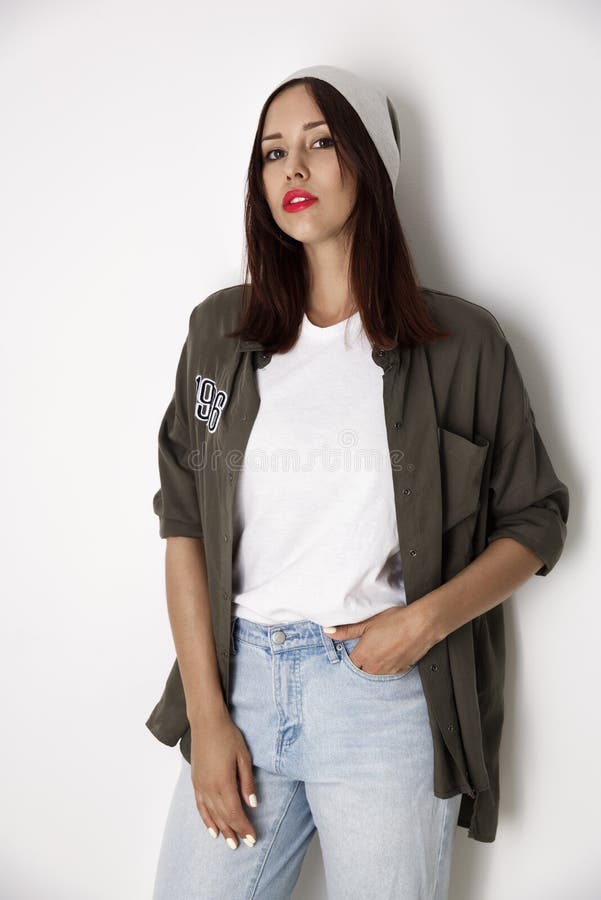 Fashionable, swarthy girl in a white T-shirt, shirt and jeans isolated on a red background. Fashionable, swarthy girl in a white T-shirt, shirt and jeans isolated on a red background