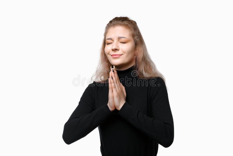 一位年轻女子闭着眼睛祈祷，恳求大家不要为站在白色背景上的人而担心 免版税库存照片