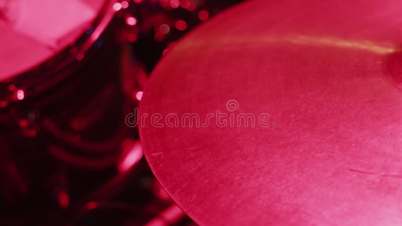 一位音乐家在一件高帽装置上演奏棒子的特写，粉红灯照亮，这是彩排的概念