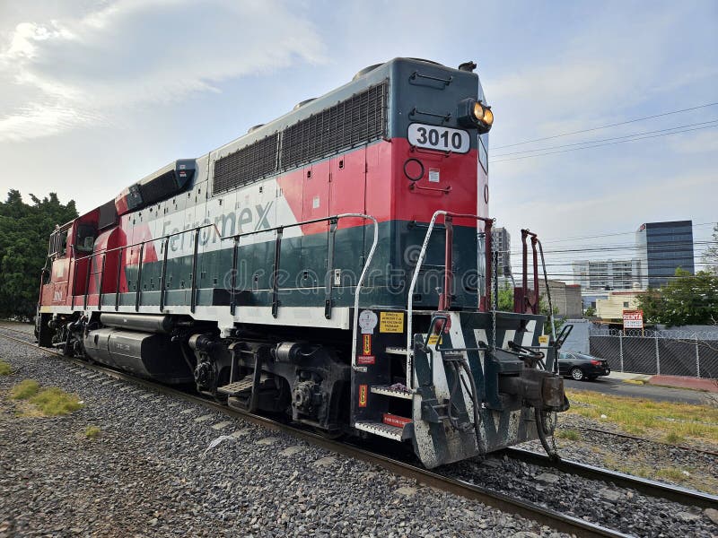 Guadalajara, Mexico -April 15 2024: A train with the number 3010 on it is parked on the tracks. The train is red and green and is on a city street. Guadalajara, Mexico -April 15 2024: A train with the number 3010 on it is parked on the tracks. The train is red and green and is on a city street