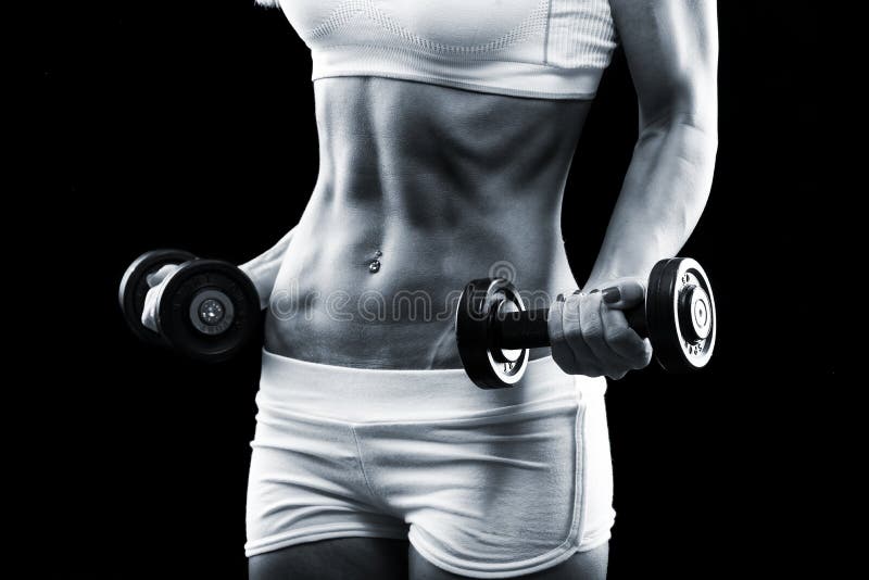 Body of a young fit woman lifting dumbbells on dark background. Body of a young fit woman lifting dumbbells on dark background