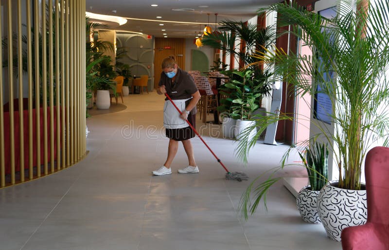 一名戴着防护面具的清洁工把酒店更宽的地板擦干净